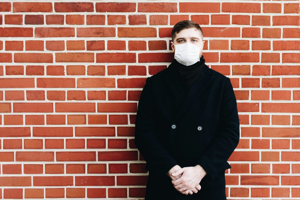 Man in front of a brick wall wearing a face mask.