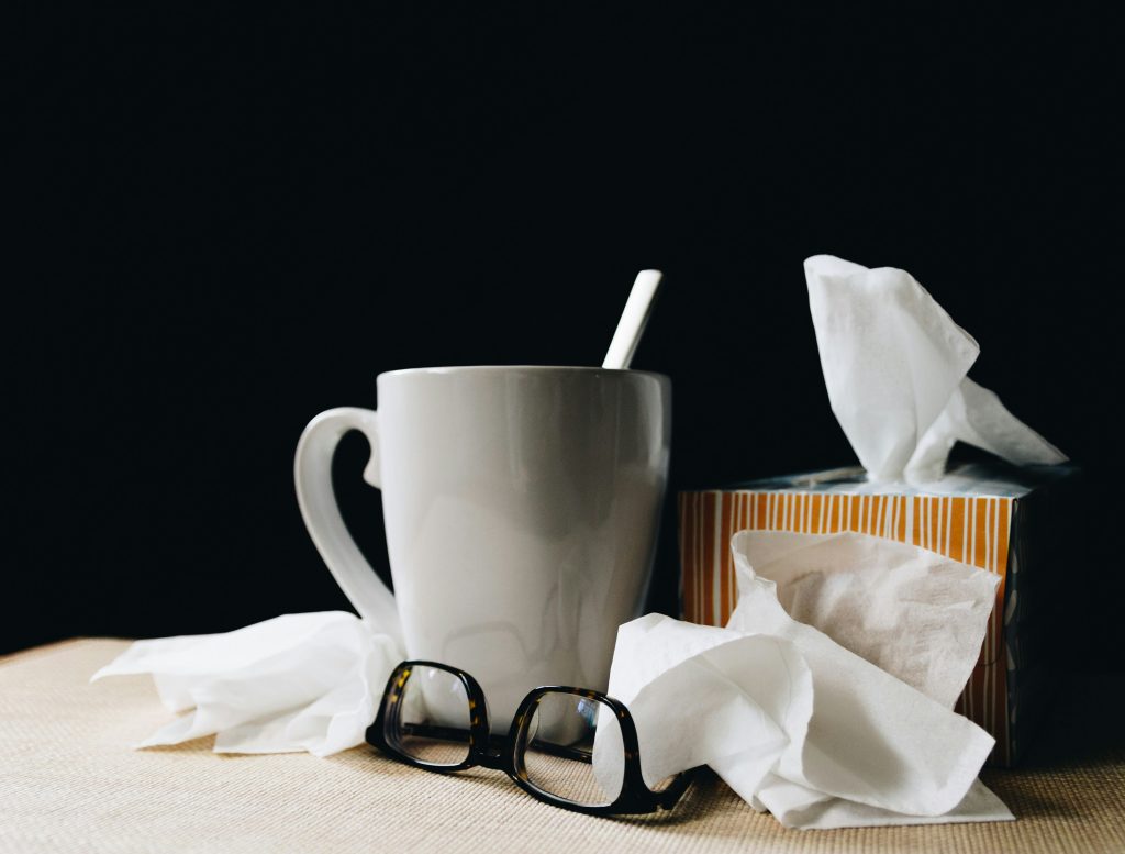 Tissues and tea on a bedside table.